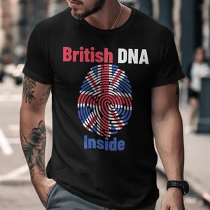 Op de afbeelding: Zwart T-shirt met de tekst "British DNA Inside". Het ontwerp toont een vingerafdrukpatroon in de kleuren van de Britse vlag. De tekst "British" is rood en "Inside" is blauw.