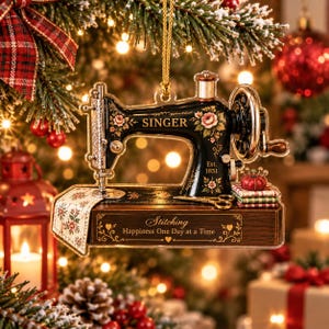 Könnte beinhalten: Ein flaches, dekoratives Ornament in Form einer schwarzen Vintage-Nähmaschine der Marke Singer mit Blumenmotiven. Es trägt die Aufschrift 'SINGER', 'Est. 1851' und 'Stitching Happiness One Day at a Time'. Inklusive kleiner Schere und Stoffstapel.