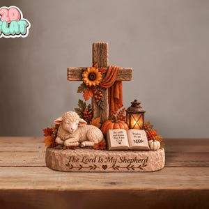 May include: A decorative tabletop sculpture featuring a wooden cross adorned with sunflowers and autumn leaves, a resting lamb, a small pumpkin, a lantern, and an open book with the text Be still and know that I am God Psalm 46:10.
