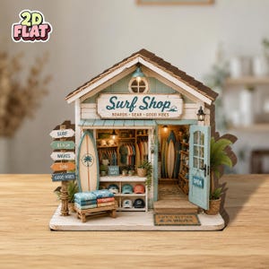 Pode incluir: Um modelo de loja de surf em miniatura de madeira com uma placa que diz Surf Shop BOARDS GEAR GOOD VIBES. A estrutura inclui uma porta azul-clara com uma placa de OPEN, uma prancha de surf, pilhas de camisas dobradas, bonés e um tapete.