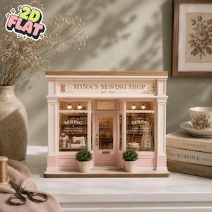 Può includere: Un modello in miniatura del Mina's Sewing Shop con una vetrina rosa chiaro e bianca, grandi finestre espositive, una porta centrale e illuminazione interna. L'insegna recita Mina's Sewing Shop Est. 19XX, con testo a tema cucito sul vetro.