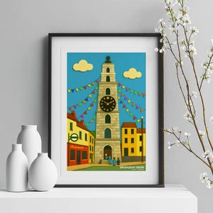 Puede incluir: Impresión artística enmarcada que presenta una colorida ilustración de una torre del reloj con una esfera, adornada con banderines festivos. La obra de arte representa edificios en tonos amarillos, rojos y azules, bajo un cielo azul con nubes. El texto "Shandon Bells" es visible.