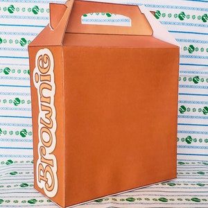 May include: A brown cardboard box with a handle and the word "Brownie" printed on the side.
