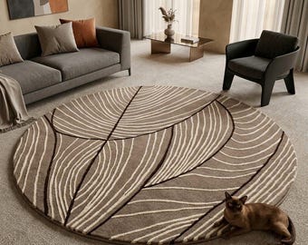 May include: A large circular area rug featuring a taupe background with a pattern of dark brown and cream-coloured curved lines that resemble abstract leaf veins. A small brown cat is lying on the edge of the rug in the lower right corner.