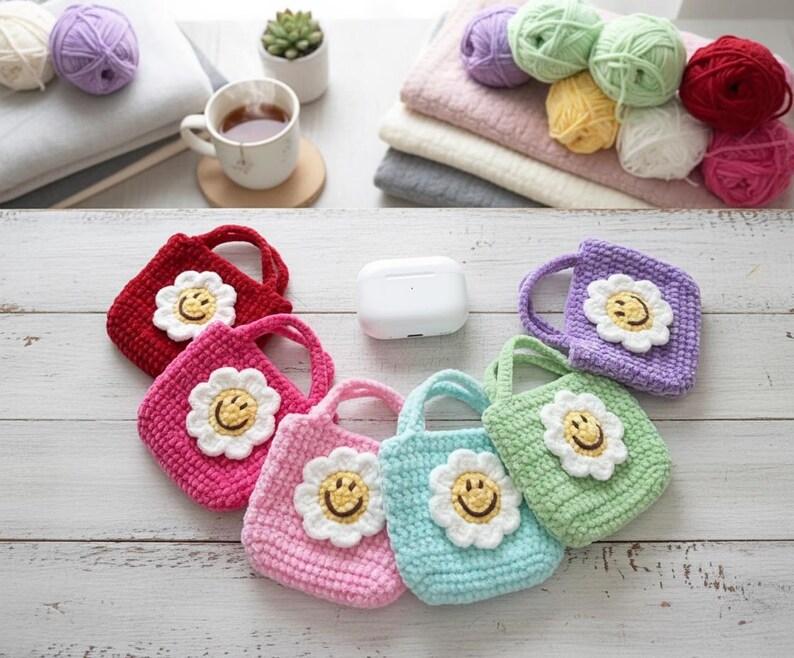 K&ouml;nnte beinhalten: Eine Sammlung farbenfroher, geh&auml;kelter Mini-Tragetaschen, jede mit einem l&auml;chelnden G&auml;nsebl&uuml;mchen-Applikation verziert. Die Taschen sind in den Farbt&ouml;nen Rot, Rosa, Lila, Blau und Gr&uuml;n gehalten. Das Bild enth&auml;lt auch Wollkn&auml;uel, eine Tasse Tee und eine kleine Sukkulente.