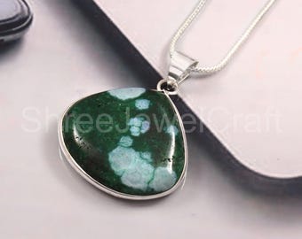 May include: A pendant necklace featuring a triangular, green gemstone with light blue inclusions, set in a silver-colored metal frame. The necklace has a delicate silver chain. The gemstone has a unique, organic pattern.