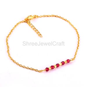 May include: A gold bracelet featuring a fine chain and a line of small, faceted red beads. The bracelet has an adjustable clasp. The text "ShreeJewelCraft" is visible on the image.