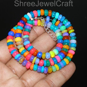 Puede incluir: Un collar multicolor de varias hebras con un arcoíris de colores. El collar está compuesto por pequeñas cuentas redondeadas en tonos de rojo, naranja, amarillo, verde, azul y morado. Un cierre plateado asegura el collar. El texto "Shree JewelCraft" es visible en la parte superior.