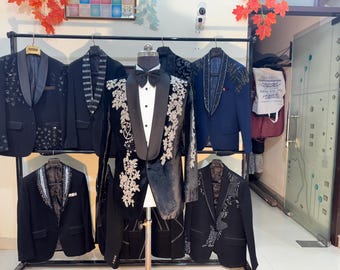 May include: A display of formal jackets and blazers, including a black tuxedo with floral embroidery and a bow tie. Other jackets feature sequin and patterned details. The jackets are displayed on a clothing rack.