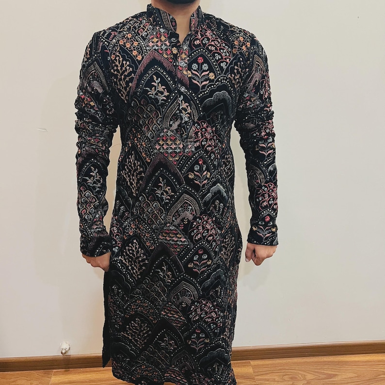 May include: Black long-sleeve tunic with intricate embroidered patterns in shades of red, pink, and gold. The tunic features a mandarin collar and a button-down front. The design is a mix of floral and geometric shapes, creating a detailed and ornate look.