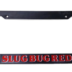 Puede incluir: Marco de matrícula de plástico negro con las palabras "Slug Bug Red" en letras rojas.