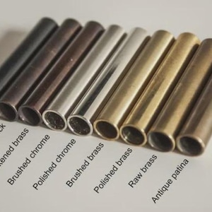May include: An assortment of metal tubes in various finishes, including matte black, antique black, and polished chrome. The tubes are arranged in a row, showcasing different colors and textures. Text labels identify each finish.