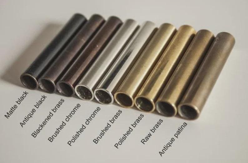 May include: An assortment of metal tubes in various finishes, including matte black, antique black, and polished chrome. The tubes are arranged in a row, showcasing different colors and textures. Text labels identify each finish.
