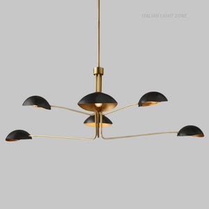 Pode incluir: Um candelabro moderno com acabamento dourado e abajures pretos. A lumin&aacute;ria possui um cubo central com v&aacute;rios bra&ccedil;os que se estendem para fora, cada um segurando uma luz preta em forma de c&uacute;pula. O texto "ITALIAN LIGHT ZONE" &eacute; vis&iacute;vel.