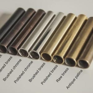 May include: A selection of metal tubes in different finishes, such as matte black, antique black, and polished chrome. The image showcases a variety of colours and textures, with labels indicating each finish. The tubes are arranged diagonally.