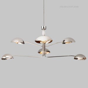 Pode incluir: Um candelabro moderno cromado com seis lumin&aacute;rias hemisf&eacute;ricas. As luzes est&atilde;o dispostas em bra&ccedil;os curvos que se estendem a partir de um centro. O texto "ITALIAN LIGHT ZONE" &eacute; vis&iacute;vel no canto superior direito.