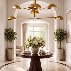 Pode incluir: Uma entrada elegante com um candelabro dourado, uma mesa redonda de madeira escura com um arranjo floral e plantas em vasos. O ch&atilde;o de m&aacute;rmore tem um padr&atilde;o circular. O texto "ITALIAN LIGHT ZONE" &eacute; vis&iacute;vel.