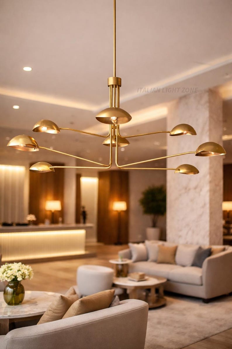 Pode incluir: Um lustre moderno dourado com v&aacute;rios bra&ccedil;os curvos, cada um com uma lumin&aacute;ria em forma de c&uacute;pula. A lumin&aacute;ria est&aacute; suspensa no teto em um espa&ccedil;o interior bem iluminado. O texto "ITALIAN LIGHT ZONE" &eacute; vis&iacute;vel.
