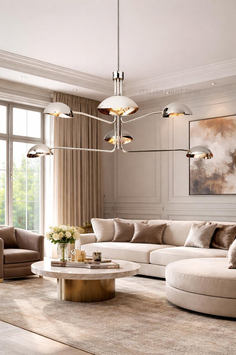 Pode incluir: Um lustre moderno com acabamento cromado polido e seis luzes em forma de c&uacute;pula. A lumin&aacute;ria pende sobre uma sala de estar com um sof&aacute; branco, uma mesa de centro redonda e uma decora&ccedil;&atilde;o em tons neutros. O texto "ITALIAN LIGHT ZONE" &eacute; vis&iacute;vel.