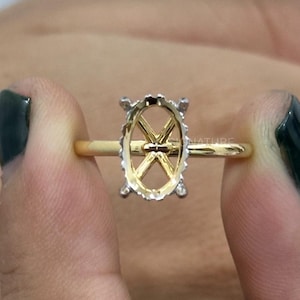 May include: A gold ring featuring an oval-shaped prong setting in silver tone. The ring band is thin and polished gold. The text SIGNATURE Elegance in you is visible in the upper left corner of the image.