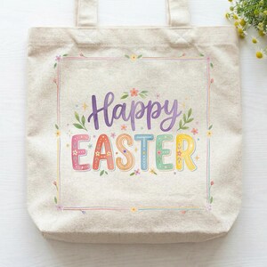 Puede incluir: Un bolso tote de lona beige con las palabras "Happy EASTER" en letras coloridas y caprichosas. El texto está enmarcado por un delicado borde floral con acentos pastel, perfecto para la Pascua.