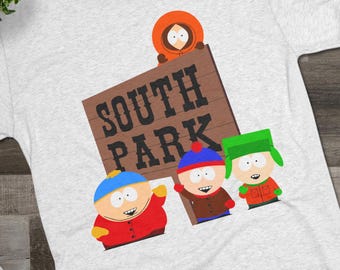 May include: A light gray t-shirt featuring the South Park characters and the show's logo on a wooden sign. The shirt has a crew neck and short sleeves. Black sneakers and glasses are also in the image.
