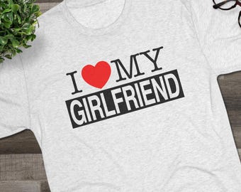 May include: A light gray heathered short-sleeve t-shirt featuring the black text I MY and the word GIRLFRIEND printed in black on a rectangular background, with a red heart symbol replacing the word LOVE between the words I and MY.