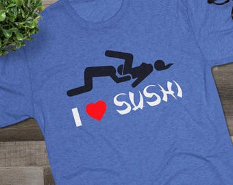 May include: A heather blue short-sleeve t-shirt featuring a black graphic of two stick figures in a suggestive pose above the white text "I" and "SUSHI" with a red heart symbol between them. The shirt has a crew neckline and a soft fabric texture.