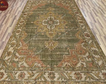 May include: An antique-style area rug with a distressed appearance. The rug features a central medallion design in shades of gold and olive green, framed by a border of peach and cream floral patterns. The rug is rectangular and appears to be made of woven material.