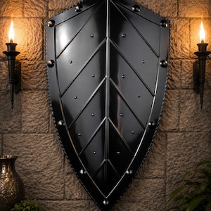 May include: A glossy black heater shield featuring a central vertical ridge and a leaf-like pattern of raised metal ribs. The shield is accented with evenly spaced silver-toned rivets along the perimeter and across the surface, with a twisted metal border.