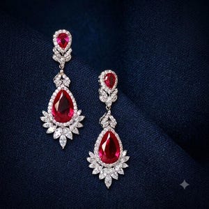 May include: A pair of drop earrings featuring a large pear-shaped red gemstone at the base, topped with a smaller pear-shaped red gemstone. Both red stones are surrounded by a halo of clear marquise and round-cut white stones in a silver setting.