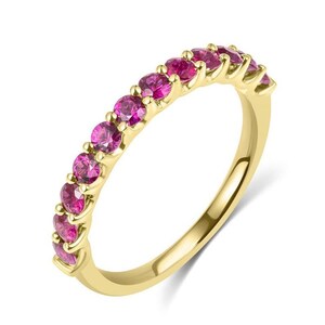 Könnte beinhalten: Ein Ring aus Gelbgold mit einer Reihe von elf runden, leuchtend pinkfarbenen Edelsteinen, die einzeln in Krappen auf der oberen Hälfte der Ringschiene gefasst sind. Das Metall hat eine polierte Oberfläche und die Steine sind in einer Reihe.