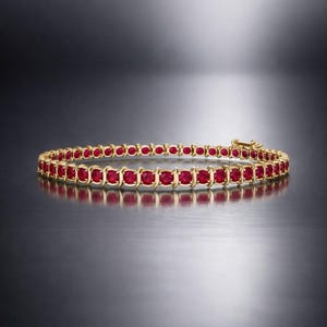 Könnte beinhalten: Ein goldenes Armband mit einer Reihe leuchtend roter Edelsteine. Die Edelsteine sind gleichmäßig verteilt und in einem goldenen Band gefasst. Das Armband wird auf einer reflektierenden Oberfläche präsentiert, was seine polierte Oberfläche hervorhebt. Ein klassisches Schmuckstück.