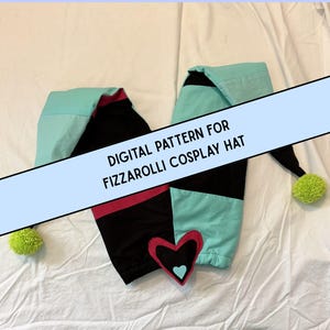 May include: A jester-style hat featuring two long, pointed sections in teal and black with a pink band. The hat includes bright lime green pom-poms at the tips and a central heart-shaped patch with a teal heart. Text reads: DIGITAL PATTERN FOR FIZZAROLLI COSPLAY HAT.