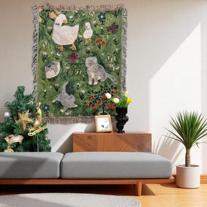 May include: A green tapestry with a whimsical design featuring geese, cats, flowers, and butterflies. The tapestry has a fringed border and is displayed on a wall. The color palette includes green, white, grey, and touches of red and purple.