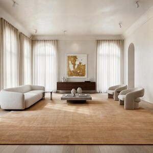 May include: A spacious living room with a neutral color palette. Features include a light-colored sofa, two armchairs, a coffee table, and a large area rug. The room is illuminated by natural light filtering through sheer curtains and recessed lighting.