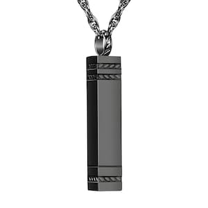 May include: A dark gray rectangular pendant necklace with a decorative leaf design on the top and bottom. The pendant hangs from a silver chain. The pendant is a long, vertical rectangle.