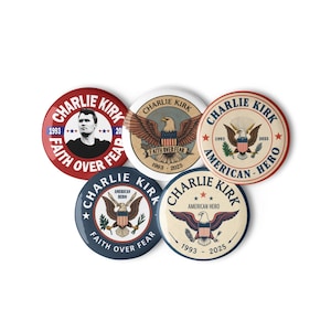 May include: A collection of five round buttons with various designs. The buttons feature the name "Charlie Kirk", an eagle, and the phrases "Faith Over Fear" and "American Hero". Colors include red, white, blue, and tan.