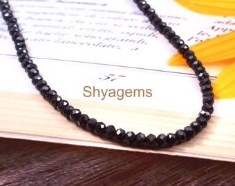May include: A black beaded necklace with a faceted design. The necklace is displayed on a book with the text "Shyagems". The beads are small and evenly spaced, creating a sleek and elegant look.