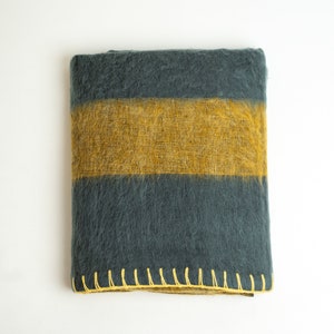 May include: A dark grey and mustard yellow striped throw blanket with a yellow stitched border.