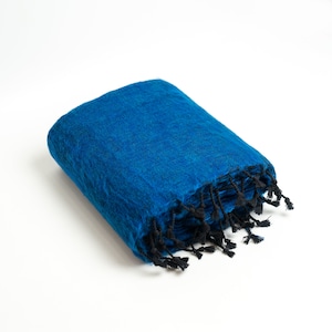 May include: A folded blue pashmina shawl with black fringe. The shawl is made of soft, luxurious wool and is perfect for adding a touch of warmth and style to any outfit.