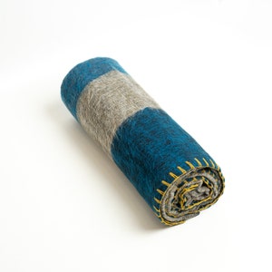 May include: A rolled up blue and gray striped blanket with yellow stitching. The blanket is made of a soft, fuzzy material.