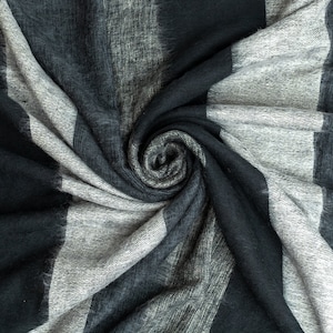 May include: A close-up of a soft, gray and black striped fabric with a swirling pattern.