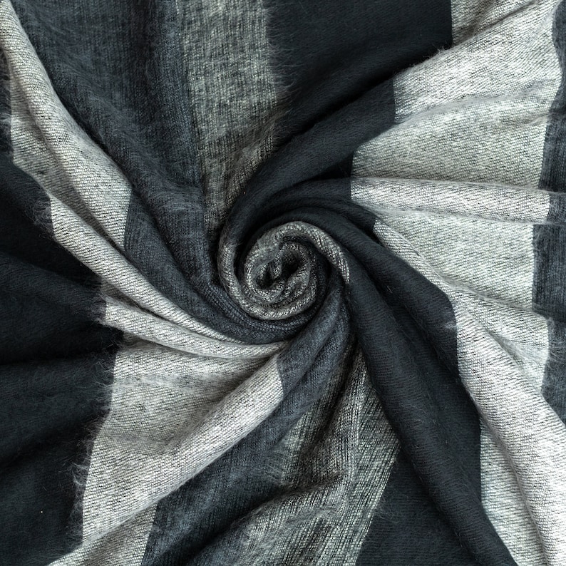 May include: A close-up of a soft, gray and black striped fabric with a swirling pattern.