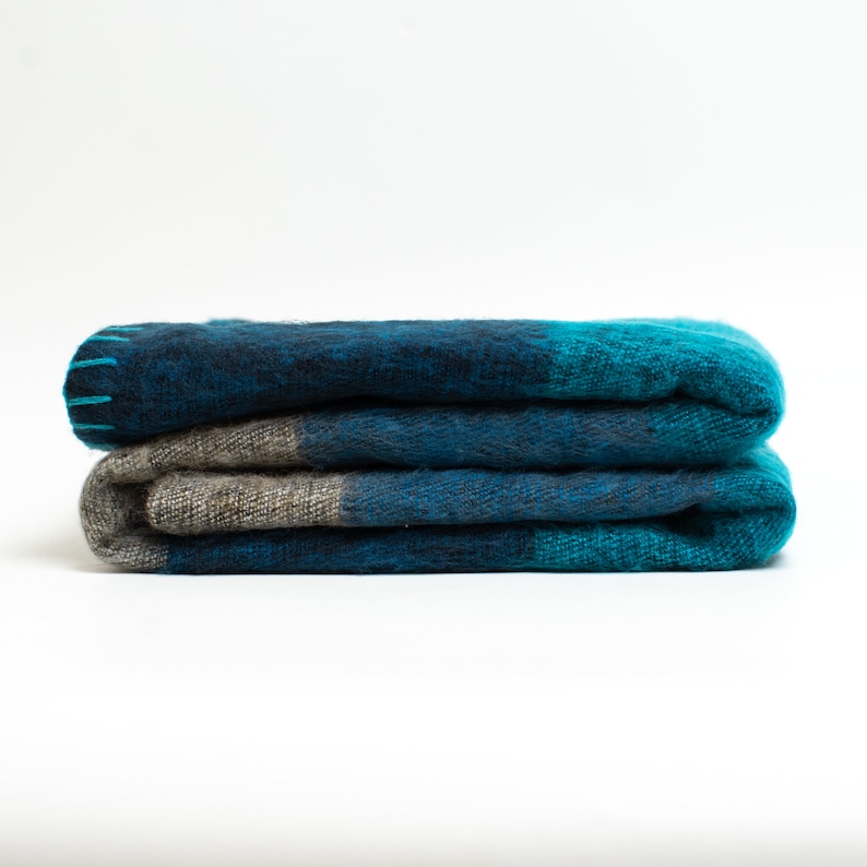May include: A folded blue and gray plaid throw blanket with a fuzzy texture.