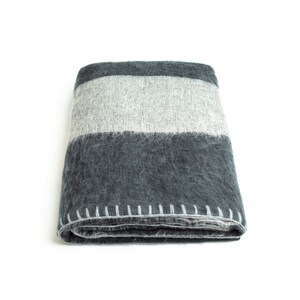 May include: A folded gray and white striped throw blanket with a stitched edge.