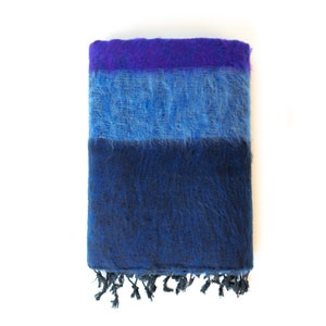 May include: A blue and purple striped pashmina shawl with fringe. The shawl is folded in half and has a soft, fuzzy texture.