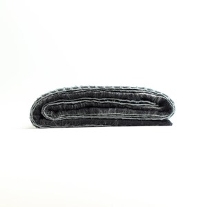 May include: A dark gray woven blanket folded in thirds, with a light gray border.