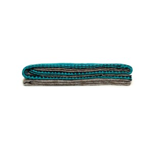May include: A folded teal and brown striped blanket. The blanket is folded in thirds and has a textured surface.