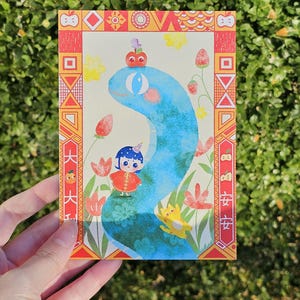 May include: A colorful postcard featuring a whimsical illustration. A blue snake-like creature is the central figure, with a small character in a red outfit. The card has a decorative border with Chinese characters and floral elements.